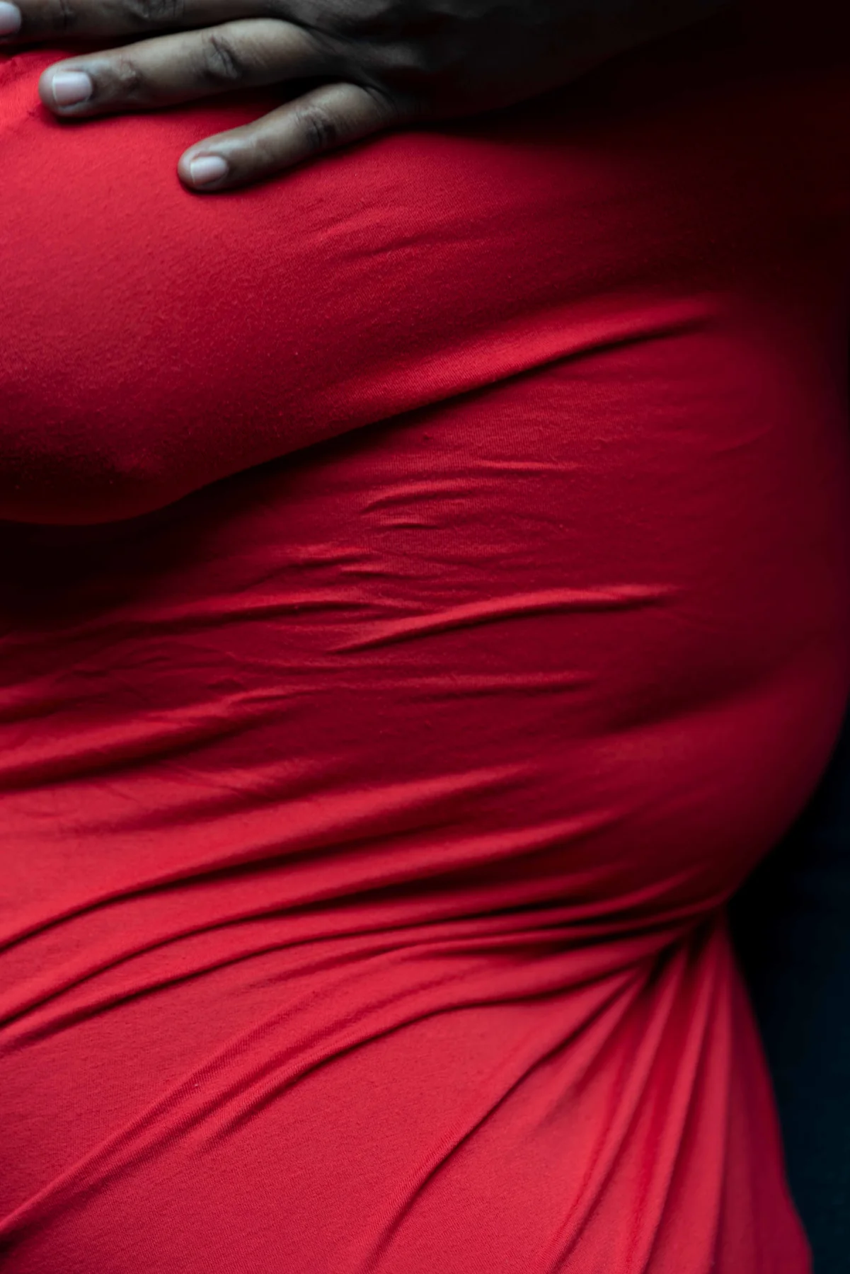A hand rests on the back of a red dress, close in and cropped tight.