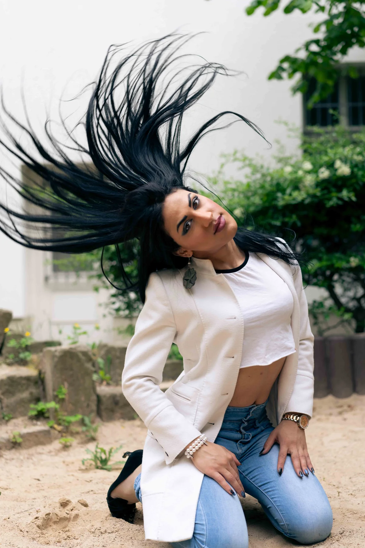 A person kneels in sunlight, dark hair thrown upward mid-motion.